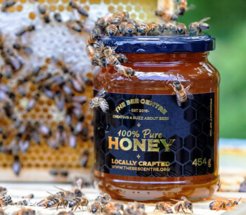 A jar of pure honey surrounded by bees