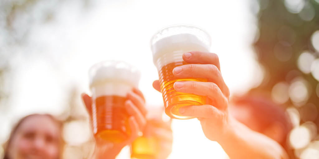 friends raising a cool glass of beer in the summer sunshine