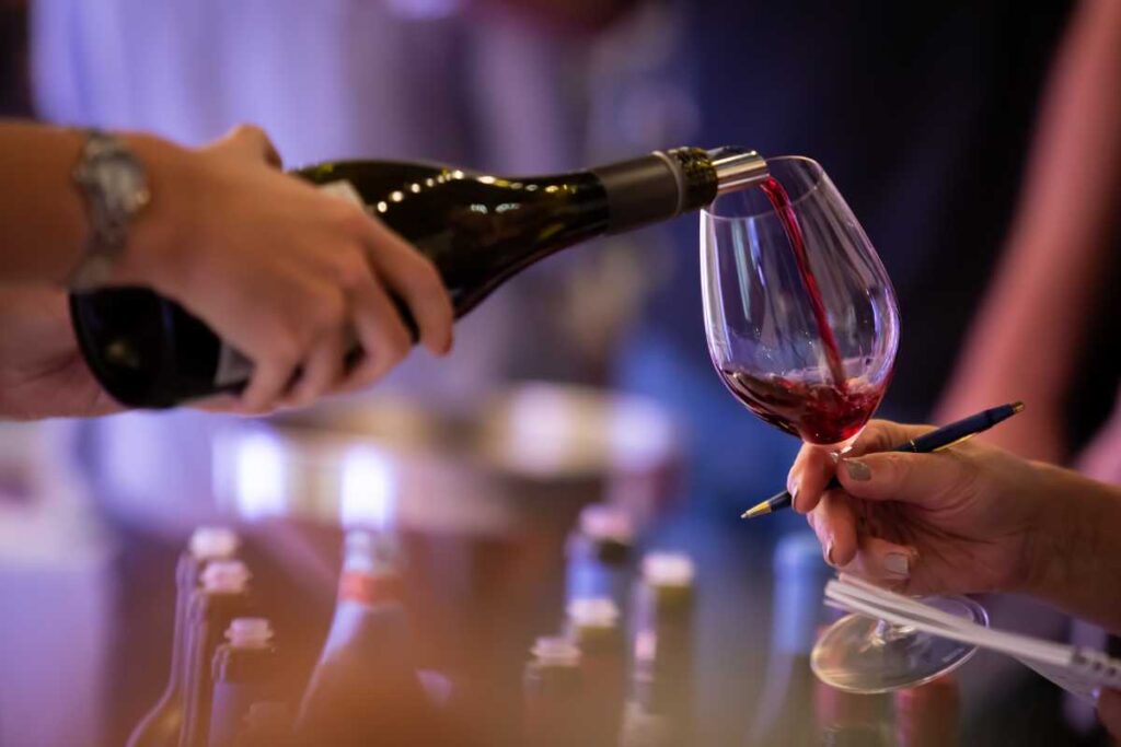 Host pouring organic wine into the glass of an awaiting guest